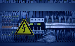 Leistungen - Automatisierungsanlagen - Wir planen, konfigurieren und montieren Prozess-Steuerungstechnik - Schaltschrankanlage mit Kabeln und dreieckigem Warnschild Hochspannung