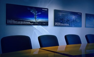 Lernen Sie uns kennen - In einem persönlichen Gespräch erfahren Sie alles was Sie wissen möchten. Rufen Sie uns jetzt an: 02838 - 814 oder -815 - Besprechungs- und Meetingraum, Vordergrund: Tisch mit Stühlen, Hintergrund: Wand mit großformatigen Keyvisuals