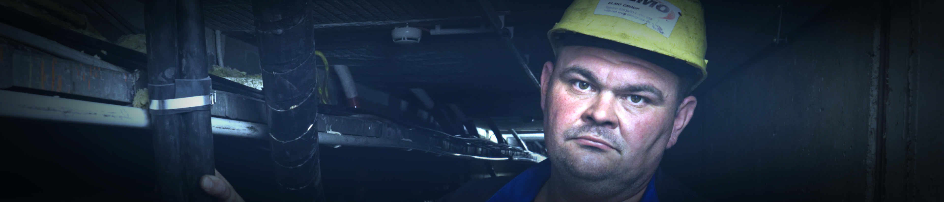 Team und Bauleiter Dieter Posniak in Kabeltunnel, mit Sicherheitshelm, Portraitausschnitt, schaut in Kamera