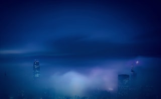 Energieinfrastruktur für Industrie und Gewerbe - Zertifizierung nach ISO 9001:2015 und SCC** - Fuer unseren hohen Qualitaetsstandard buergen unsere Zertifizierungen - Nachtaufnahme Skyline Hong Kong - nur die höchsten Wolkenkratzer ragen aus Wolkendecke hervor