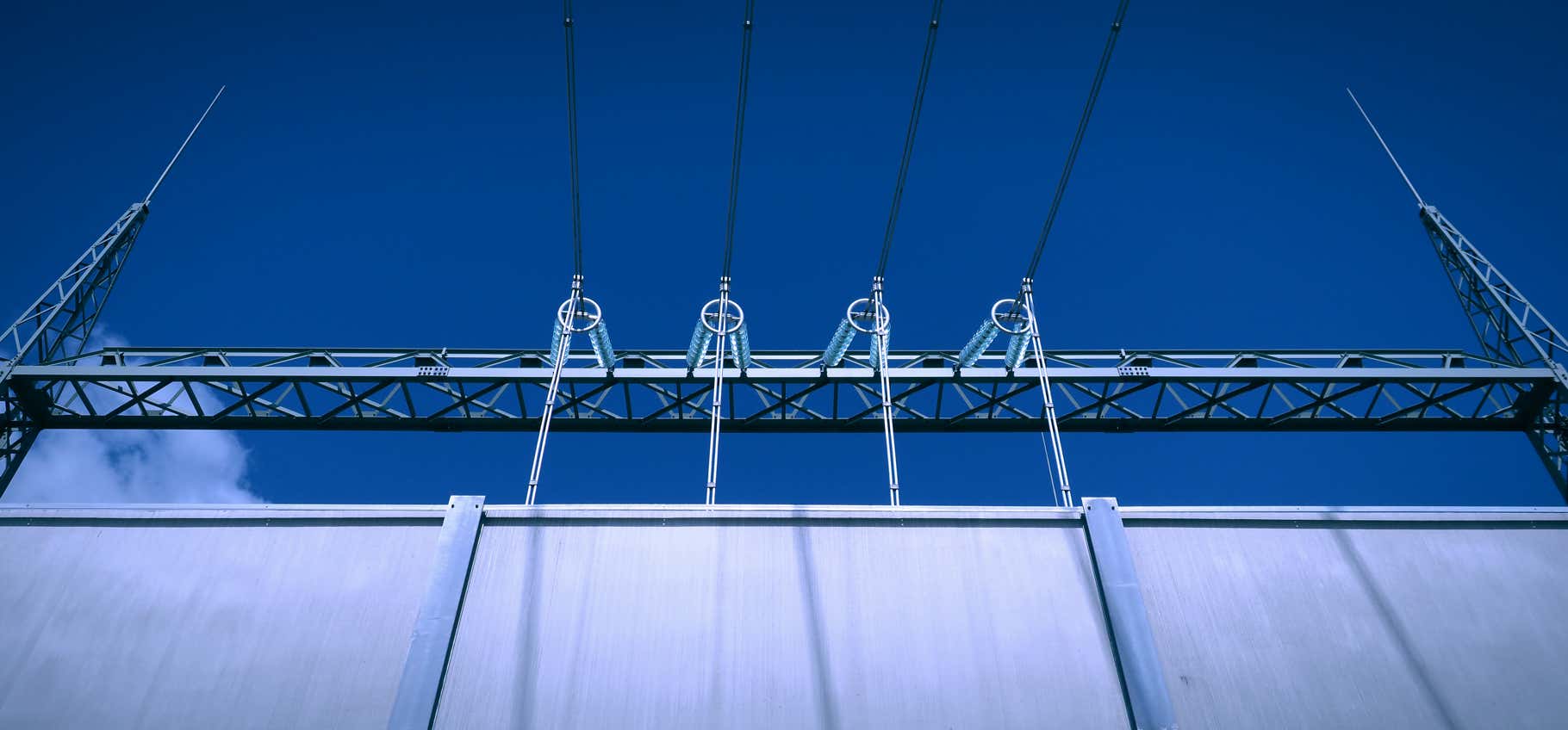 Foto Hochspannungsfreilandleitungen, Zuleitungsanlage Oel-Transformator Umspannwerk, transparente Hochspannungsisolatoren, hoeh Mauer, blauer Himmel