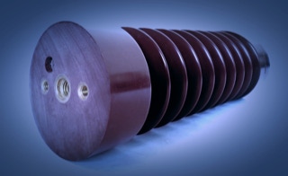 Immer griffbereit - Installationsmaterialien - In unserem Lager bevorraten wir Installationsmaterialien wie Isolatoren, Komponenten für Kabeltrag-Systeme, Kabelbühnen und den Kabelwegebau - Perspektivisch aufgenommener Isolator, braun/rot, mit Messinggewinden am unteren Ende, weißer Hintergrund mit Verlauf