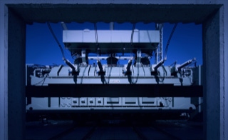 Transformatoreinbringung - Öl- und Trockentransformatoren nach Kundenanforderung - Einbringung sowie Montage der Transformator Zu- und Ableitungen - Alstom Öl-Transformator, Blick durch Beton-Bogen, blauer Himmel Mittags in Umspannwerk