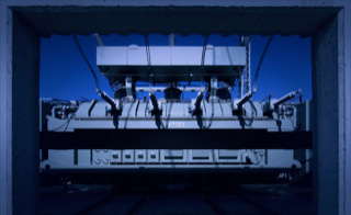Transformatoreinbringung - &Ouml;l- und Trockentransformatoren nach Kundenanforderung - Einbringung sowie Montage der Transformator Zu- und Ableitungen - Alstom &Ouml;l-Transformator, Blick durch Beton-Bogen, blauer Himmel Mittags in Umspannwerk