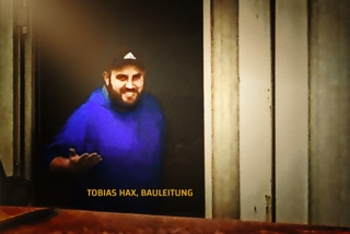 Bauleiter Tobias Hax - Bauleiter Tobias Hax mit blauem Hoody und Baseball-Cap laechelt in Kamera